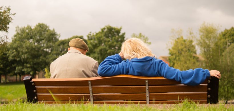 Pareja de ancianos sentados de espaldas en un banco